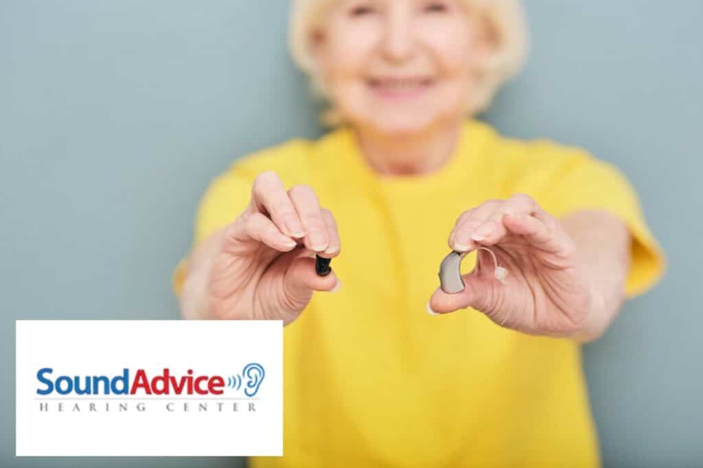 lady holding two hearing aids in front of her