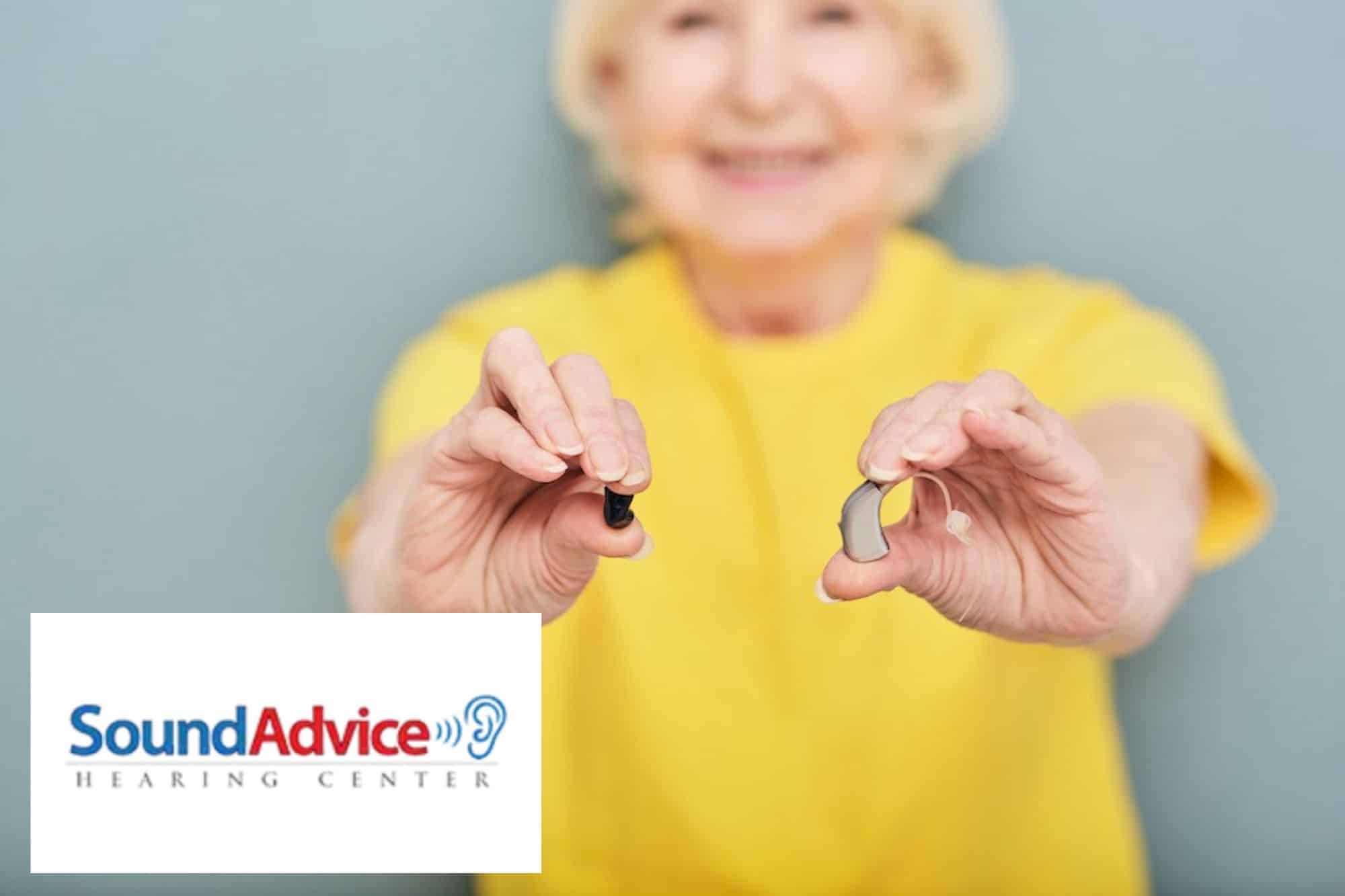 lady holding two hearing aids in front of her